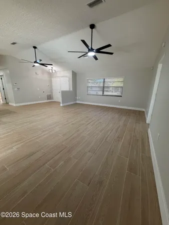 an empty room with windows and ceiling fan