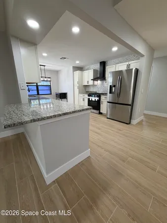 a large kitchen with stainless steel appliances granite countertop a lot of counter space and wooden floors