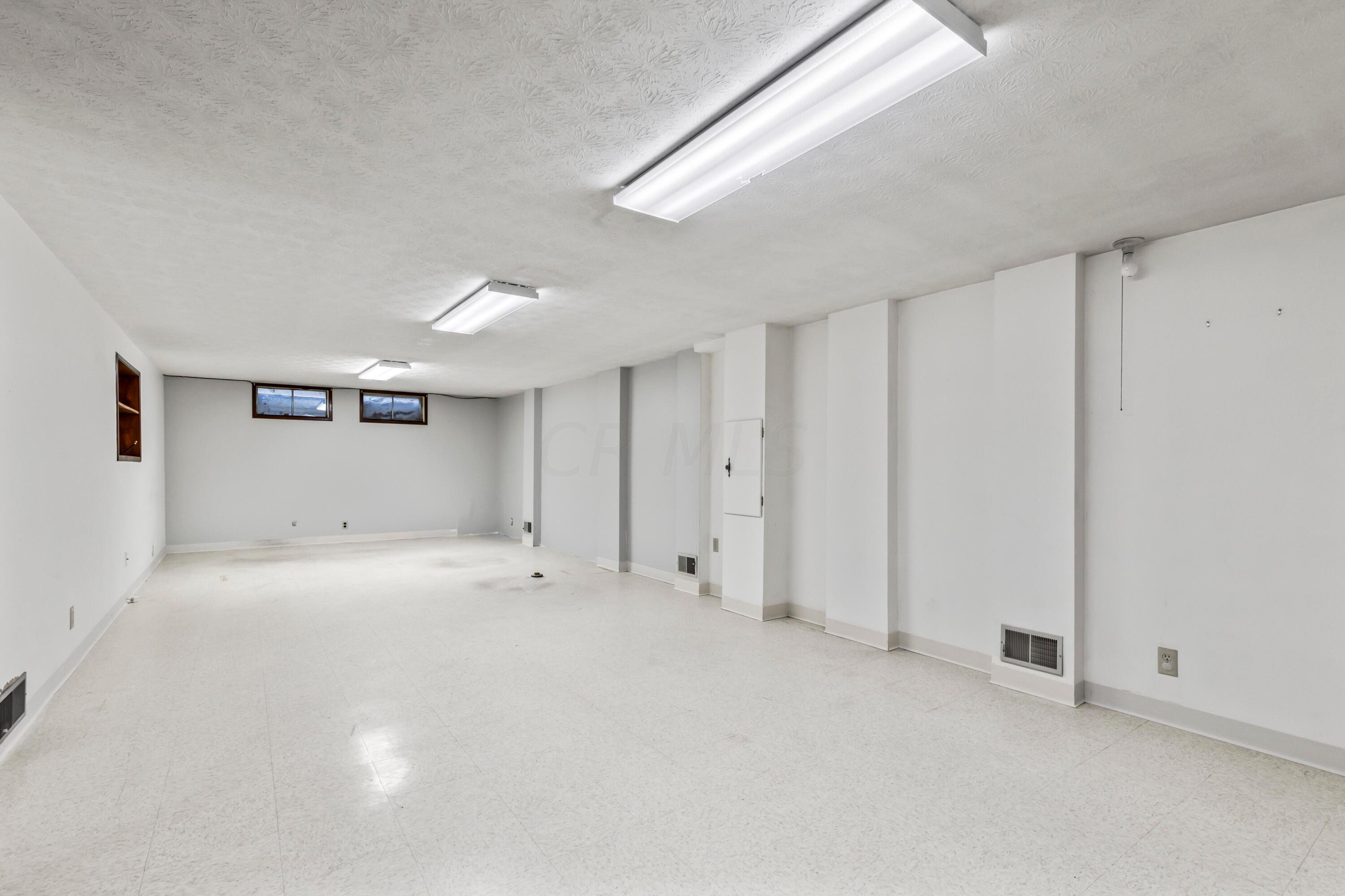 7020 Rieber Street Columbus, OH 43085 - Photo 36 of 40 • Linoleum tile flooring • Ivory painted walls • (3) New ceiling lights ~ 2017 • Two windows • Built-in bookcases