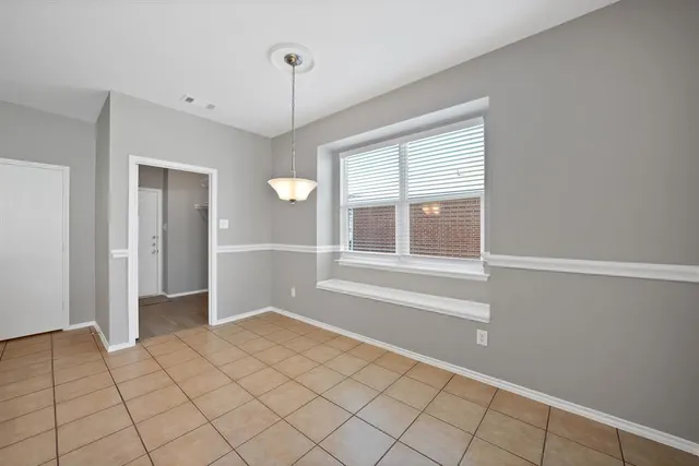 a view of an empty room with window and chandelier fan