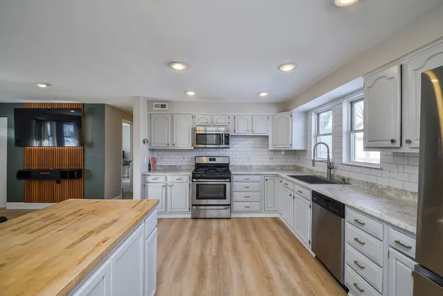 a kitchen with stainless steel appliances granite countertop sink stove refrigerator and cabinets