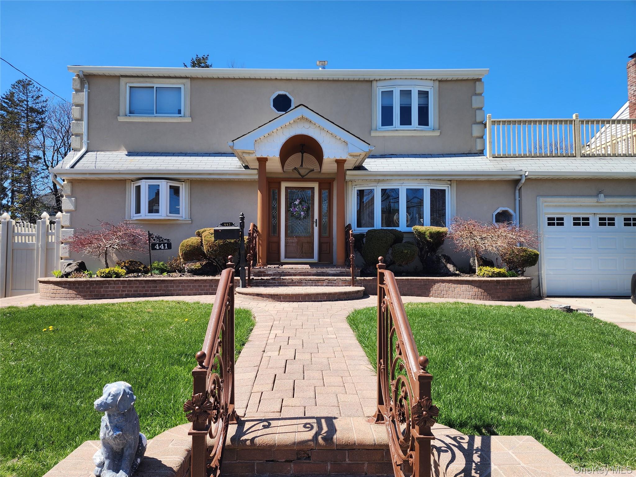a front view of a house with garden and trees