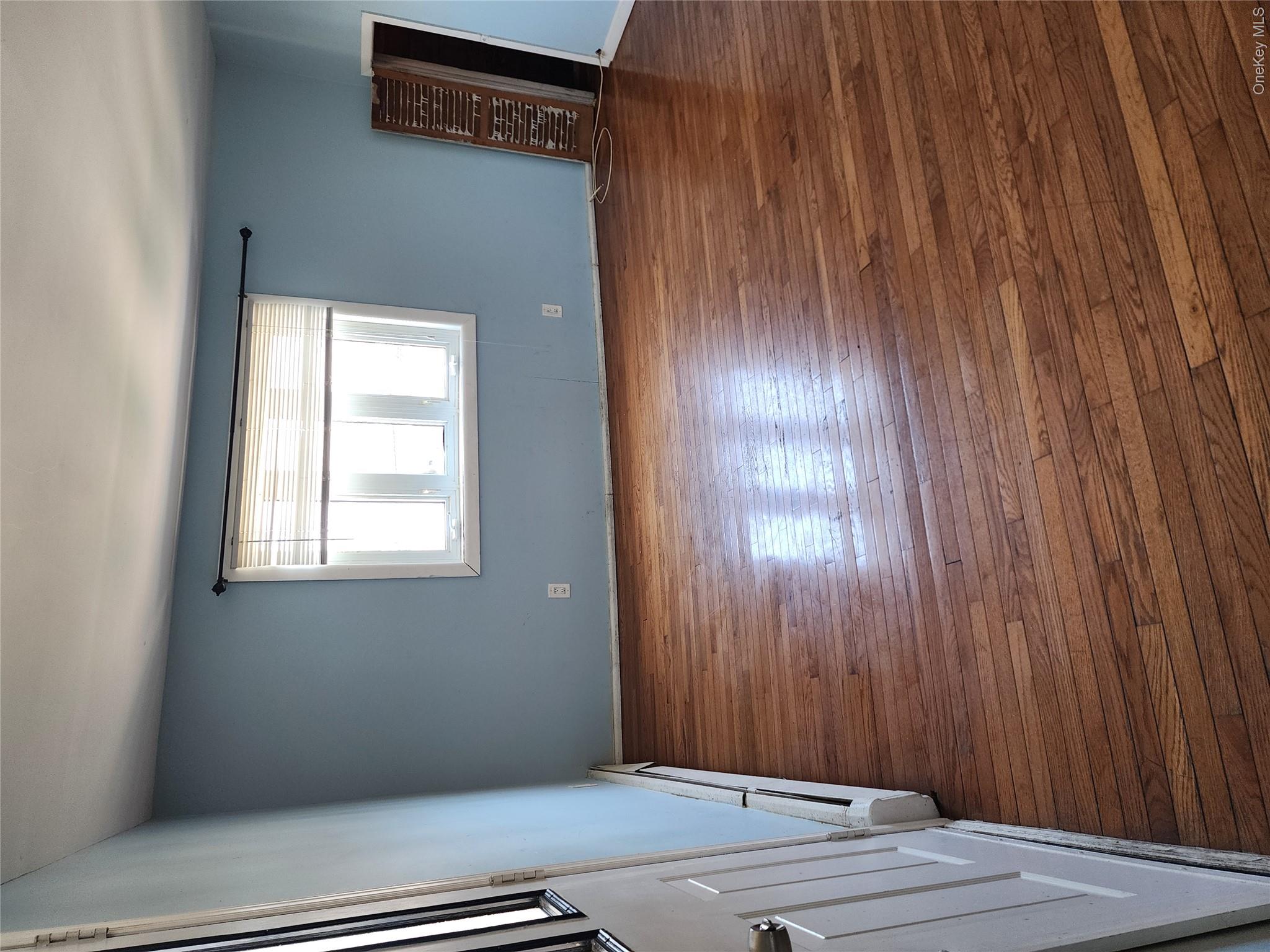441 Morris Drive Valley Stream, NY 11580 - Photo 8 of 15 an empty room with wooden floor and windows