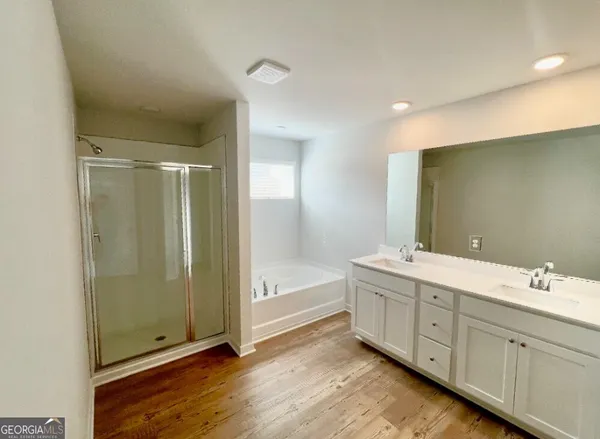 a spacious bathroom with a double vanity sink a large mirror and a bathtub