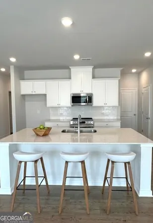 a kitchen with stainless steel appliances granite countertop a stove top oven a sink counter space and chairs