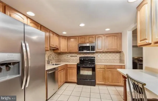 a kitchen with stainless steel appliances granite countertop a refrigerator a stove top oven a sink and dishwasher