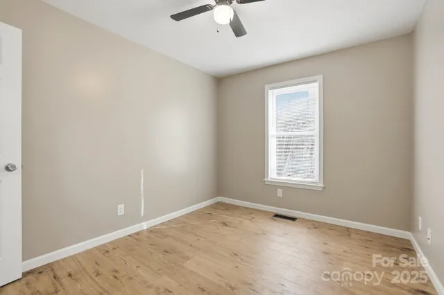 an empty room with a window and a fan