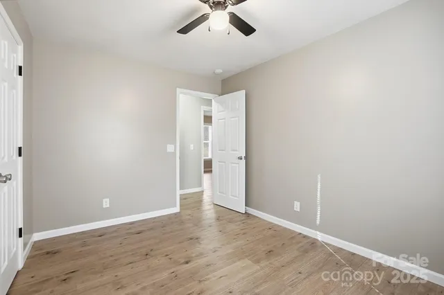 an empty room with wooden floor and ceiling fan