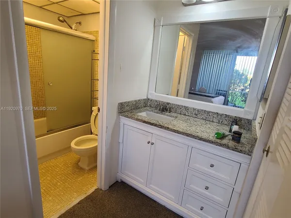 a bathroom with a granite countertop sink toilet and shower