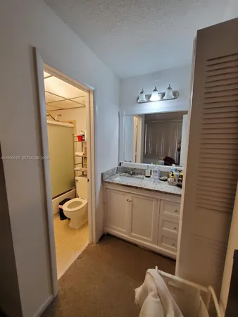 a bathroom with a granite countertop sink mirror and toilet