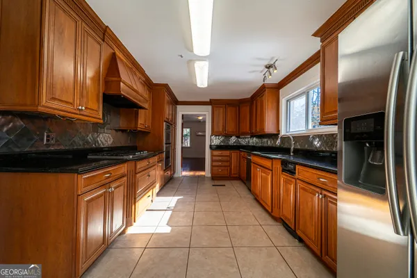 a large kitchen with stainless steel appliances granite countertop a stove a sink dishwasher and a refrigerator