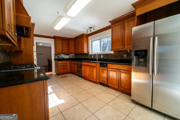 a kitchen with stainless steel appliances granite countertop a refrigerator a sink and a stove
