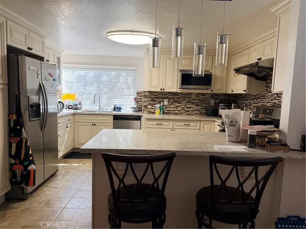 a kitchen with stainless steel appliances a table chairs stove and refrigerator