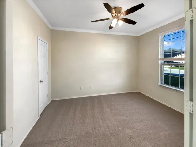a view of an empty room with window and a ceiling fan