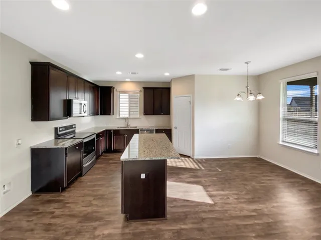 a large kitchen with stainless steel appliances granite countertop a sink and a stove top oven