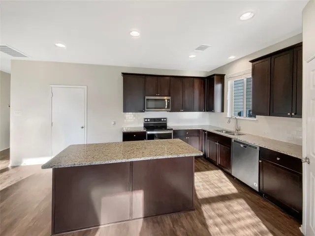 a kitchen with stainless steel appliances granite countertop a stove a sink and a microwave
