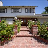 a front view of a house with a yard and potted plants