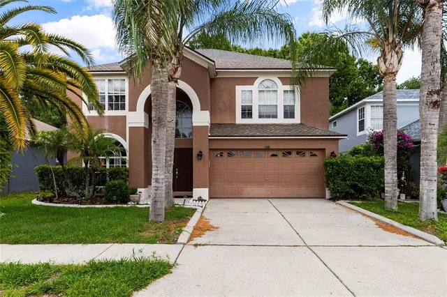 front view of house with a yard and palm trees