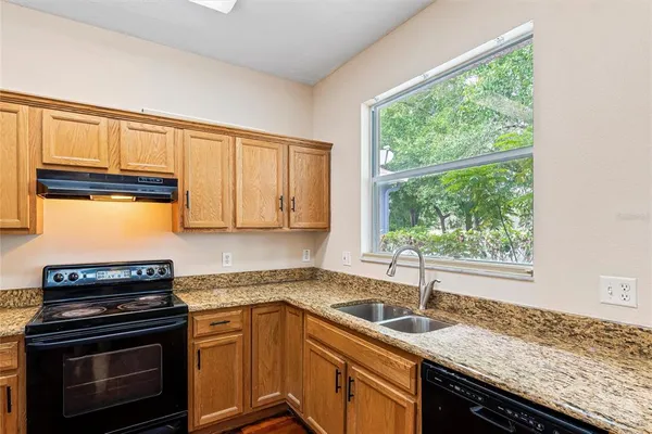 a kitchen with granite countertop a sink stove top oven and cabinets