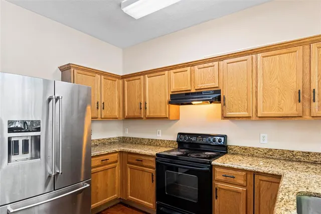 a kitchen with granite countertop a refrigerator stove and sink