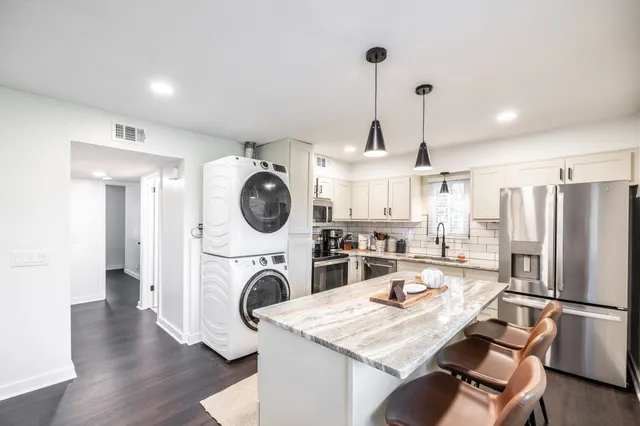 a kitchen with kitchen island stainless steel appliances a stove a sink a refrigerator wooden floor and a fireplace