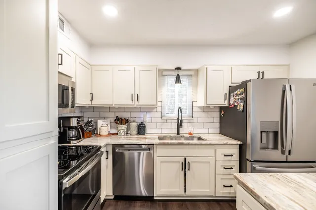 a kitchen with stainless steel appliances granite countertop a refrigerator sink and stove