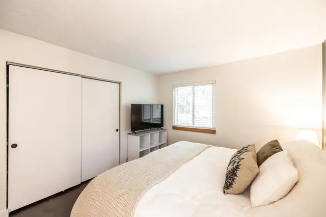 a bedroom with a bed and a flat tv screen on dresser