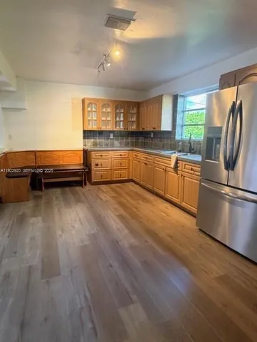 a kitchen with stainless steel appliances granite countertop a refrigerator a sink dishwasher a stove and white countertops with wooden floor