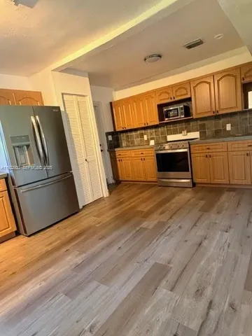 a kitchen with wooden floors and appliances
