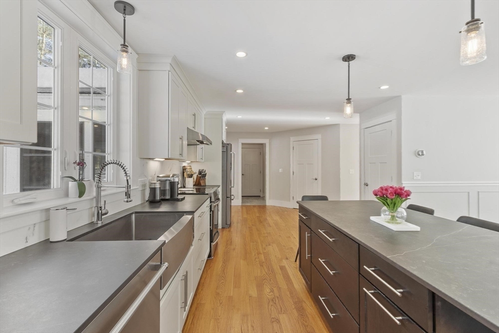 3 Swett Drive Hampton, NH 03842 - Photo 15 of 42 a kitchen with granite countertop a sink dishwasher a stove and white cabinets with wooden floor