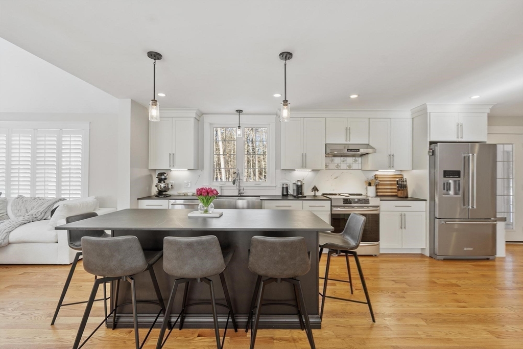 3 Swett Drive Hampton, NH 03842 - Photo 17 of 42 a kitchen with stainless steel appliances kitchen island granite countertop a table chairs stove and refrigerator