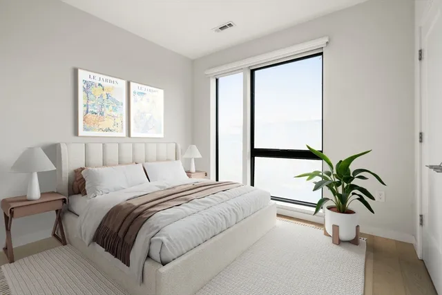 a bedroom with a large bed and a potted plant