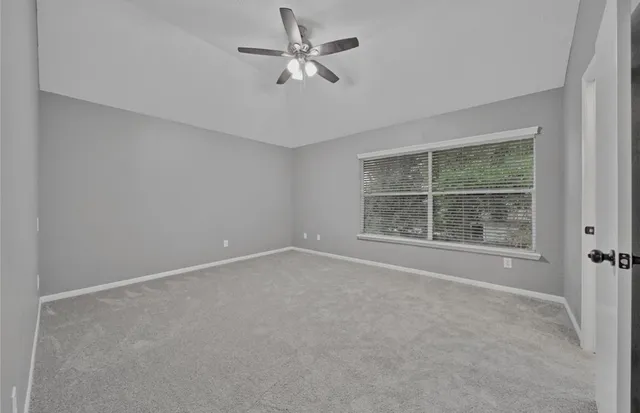 an empty room with a window and a fan