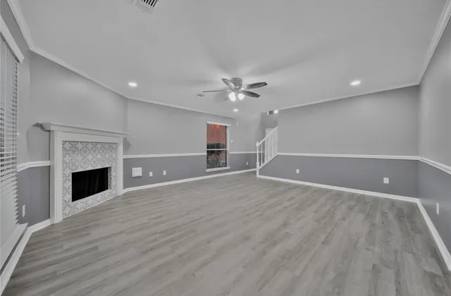 a view of an empty room with wooden floor fireplace and a window
