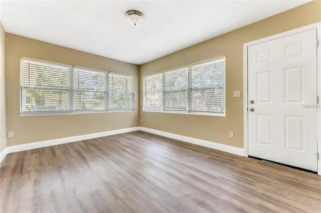 a view of an empty room with wooden floor and a window