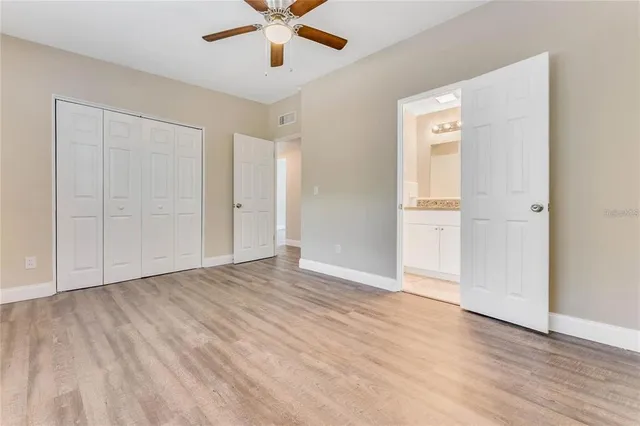 an empty room with wooden floor and a ceiling fan