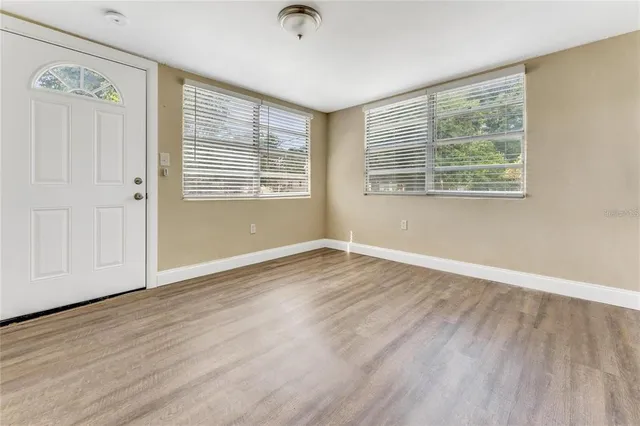 an empty room with wooden floor and windows
