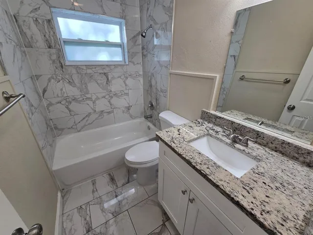 a bathroom with a granite countertop sink a toilet and bathtub