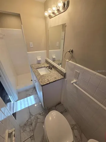 a bathroom with a granite countertop toilet sink and mirror