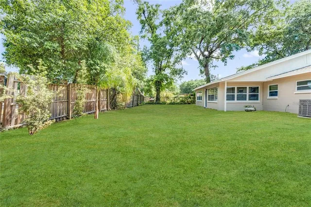 a view of a house with a big yard and large trees
