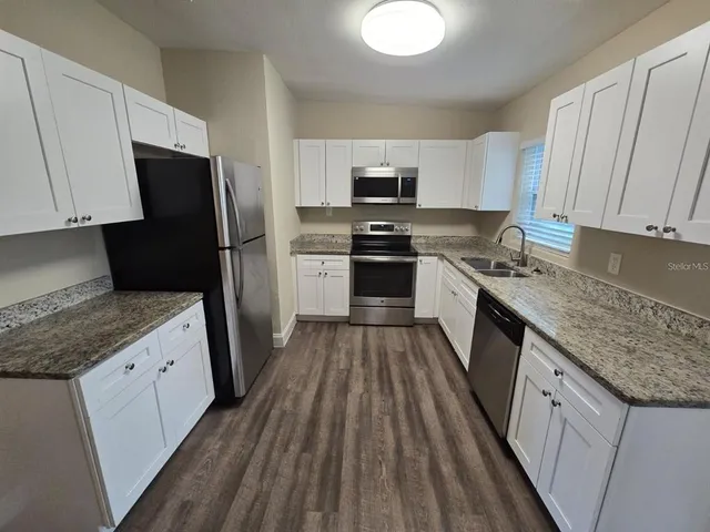 a kitchen with granite countertop a sink stove and refrigerator