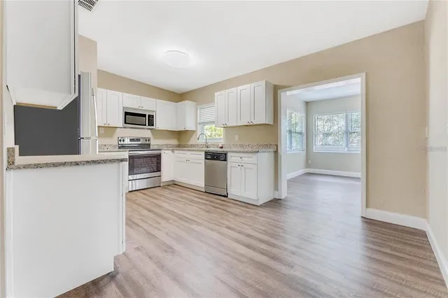 a kitchen with wooden floors and white stainless steel appliances