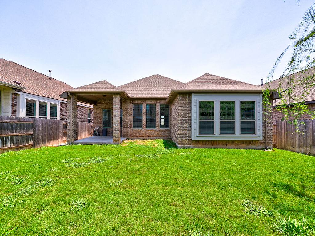 229 Heartleaf Road San Marcos, TX 78666 - Photo 5 of 40 A manicured lawn extends to a covered patio, ideal for outdoor enjoyment.