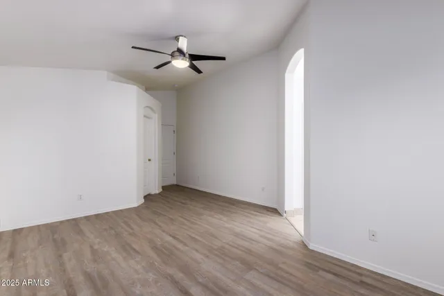 an empty room with wooden floor chandelier fan and closet area