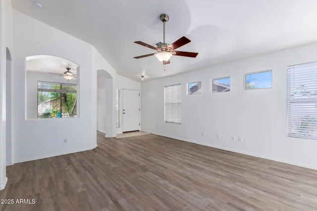 a view of an empty room with window and wooden floor