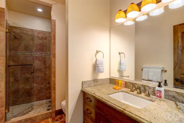 a bathroom with a granite countertop sink a mirror and shower