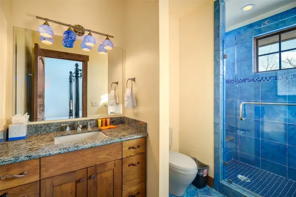 a bathroom with a granite countertop sink a toilet a mirror and shower