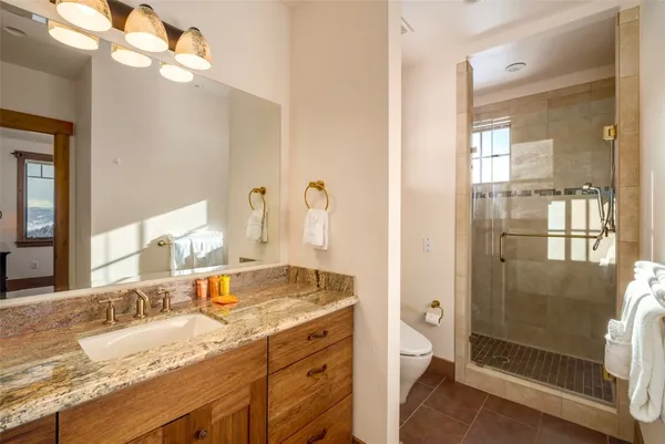 a bathroom with a granite countertop double vanity sink mirror and shower