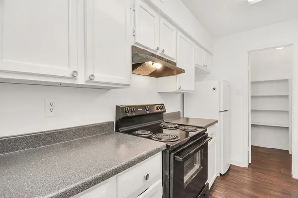 a kitchen with granite countertop a stove and a wooden floor