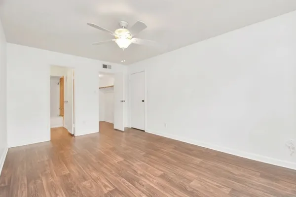 a view of a room with wooden floor and a ceiling fan